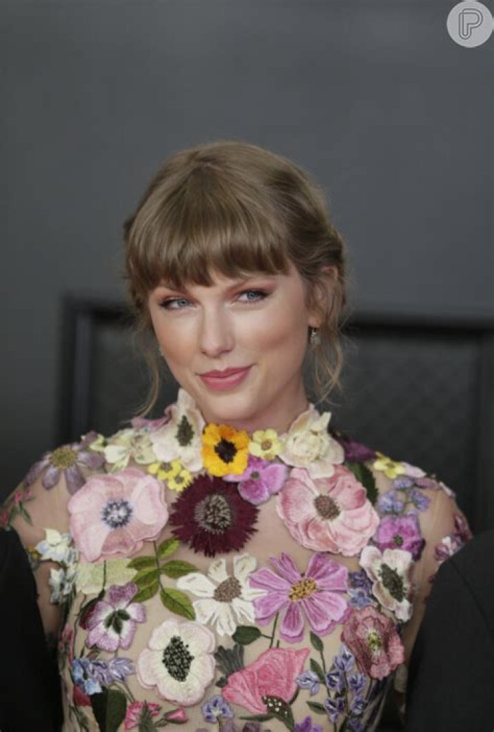 Taylow Swift aposto em penteado preso com fios desconectados e