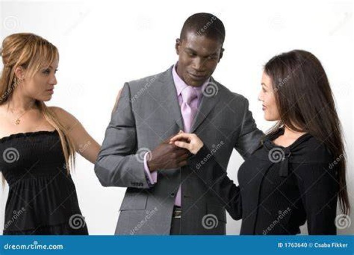 two women and a man posing on the red carpet at an event, in front of a